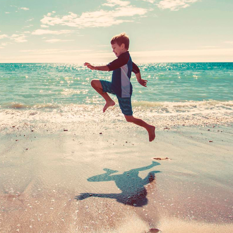 Niño saltando en la playa